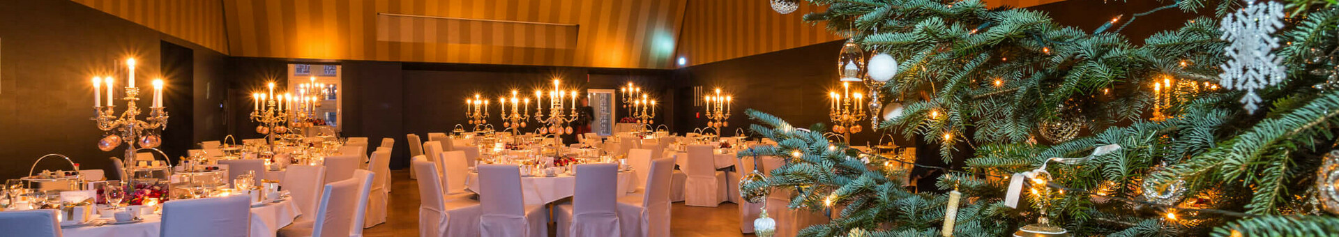 Festlich dekorierter Bankettsaal im ATLANTIC Grand Hotel Bremen mit Weihnachtsbaum und Kerzenleuchtern.