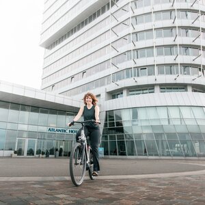 Eine Frau fährt Fahrrad vom dem ATLANTIC Hotel Sail City