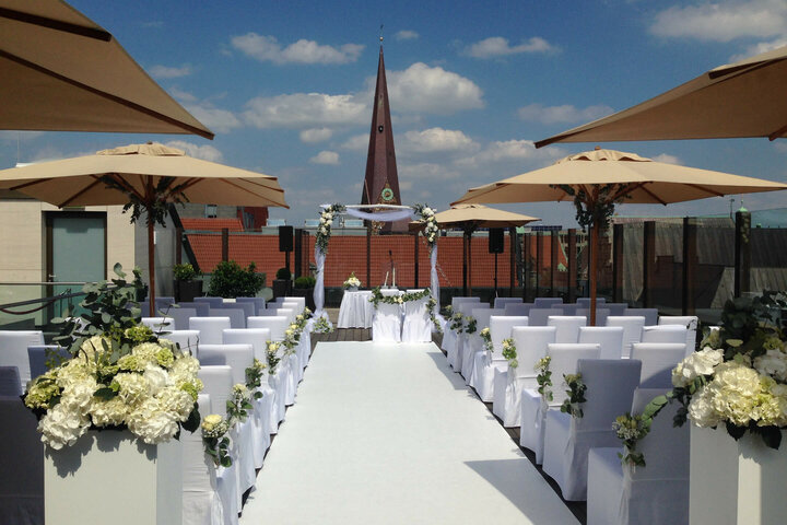 Dachterrasse des ATLANTIC Grand Hotel Bremen, festlich für eine Hochzeit dekoriert mit weißen Stühlen und Blumen.
