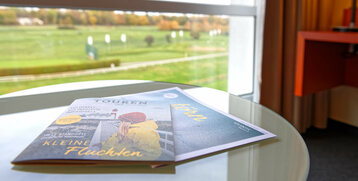 View of the racecourse from the hotel room, with magazines on a glass table in the foreground.
