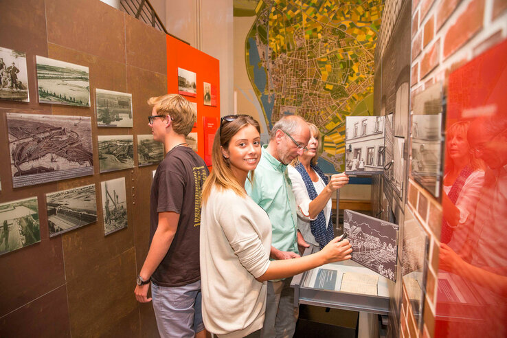 Menschen betrachten historische Fotos und Karten in einem Museum.