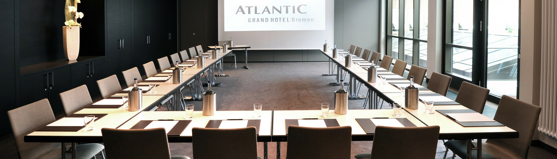 Modern conference room in the ATLANTIC Grand Hotel Bremen with U-shaped table arrangement and screen.