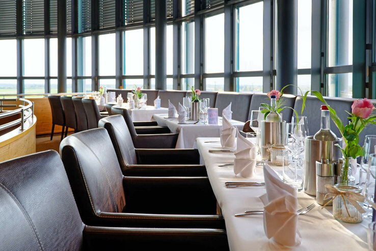 Elegant restaurant with laid tables, white tablecloths, leather armchairs and panoramic windows at the ATLANTIC Hotel Airport.
