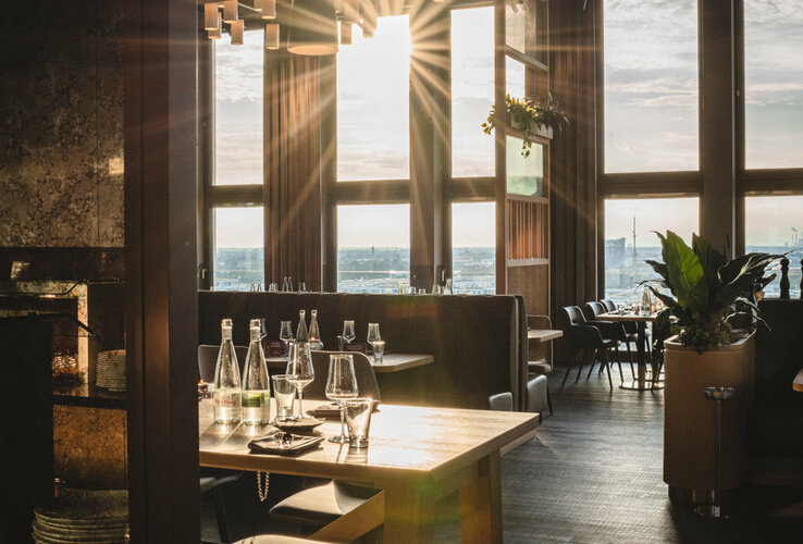 Helles Restaurant mit Sonnenlicht durch große Fenster, modern gedeckte Tische und stilvolles Interieur im ATLANTIC Hotel Heidelberg.
