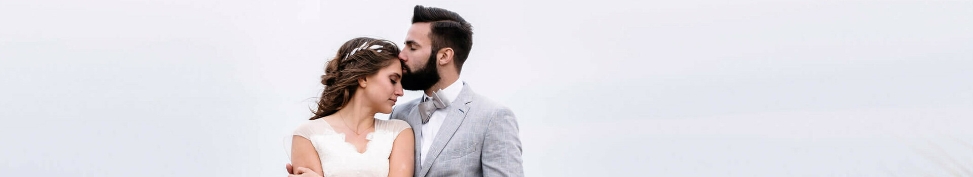 Hochzeitspaar am Strand Brautpaar am Strand, umarmt sich in hohen Gräsern mit Meerblick im Hintergrund.