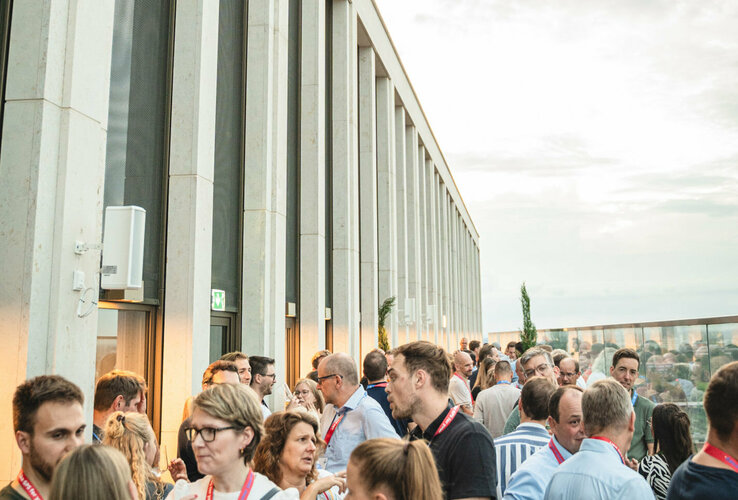Menschen bei einer Veranstaltung auf der Dachterrasse des ATLANTIC Hotel Heidelberg bei Sonnenuntergang.