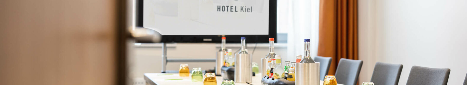 Modern conference room at the ATLANTIC Hotel Kiel with a set table and presentation screen.