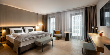 Modernes Hotelzimmer mit Doppelbett, Sitzbereich, Schreibtisch und großem Fenster, ATLANTIC Hotel Heidelberg.