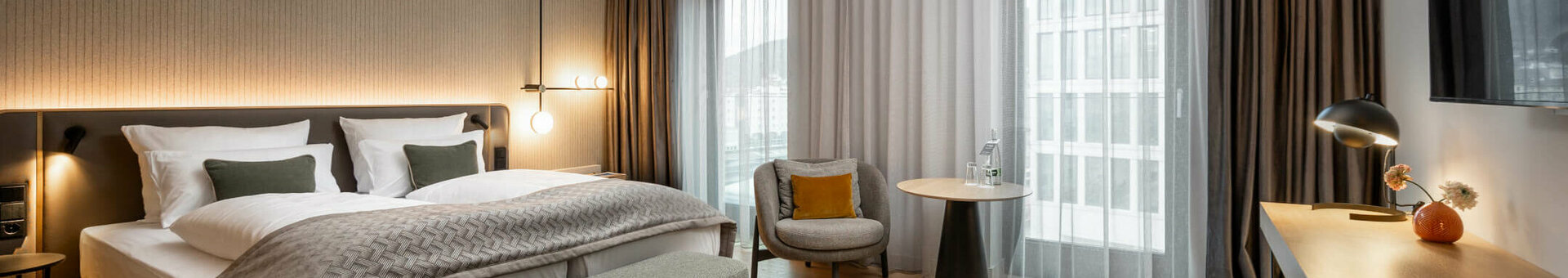 ATLANTIC Hotel Heidelberg Deluxe Room Modern hotel room with double bed, seating area, desk and large window, ATLANTIC Hotel Heidelberg.