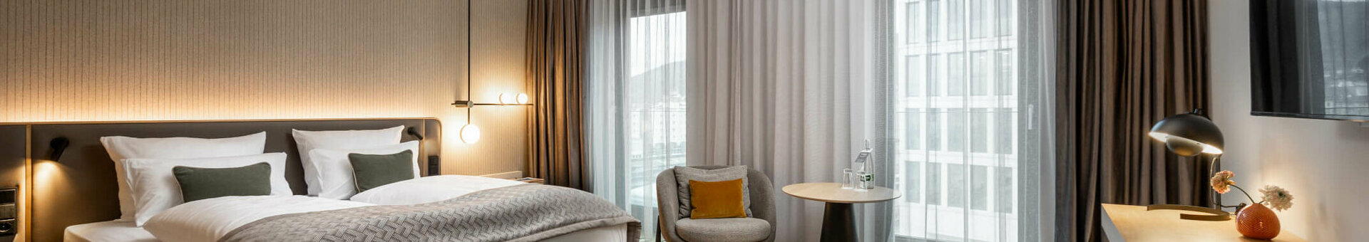 Modernes Hotelzimmer mit Doppelbett, Sitzbereich, Schreibtisch und großem Fenster, ATLANTIC Hotel Heidelberg.