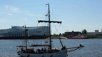 Segelschiff auf der Weser vor Industriekulisse in Vegesack bei klarem Himmel.