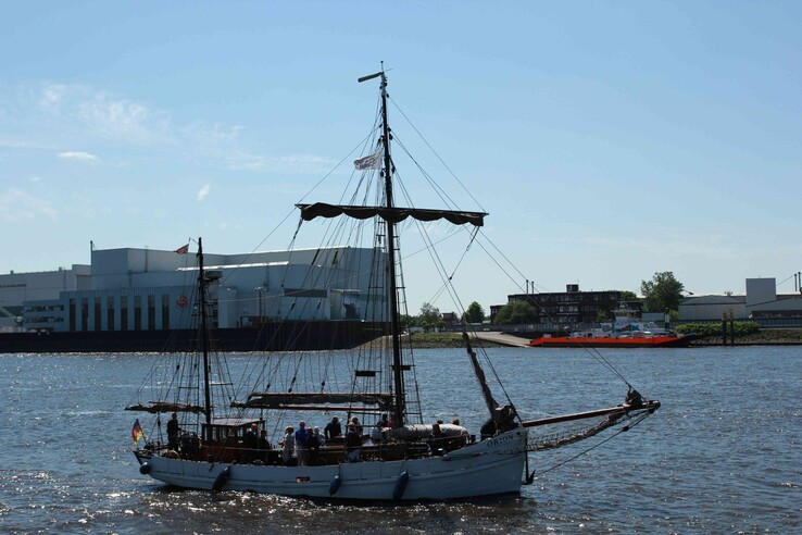 Sailing ship on the Weser against an industrial backdrop in Vegesack under a clear sky.