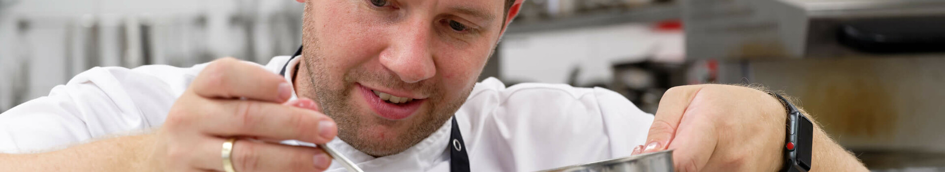 Koch verfeinert kunstvoll ein Gericht in der Küche des ATLANTIC Hotel Wilhelmshaven.