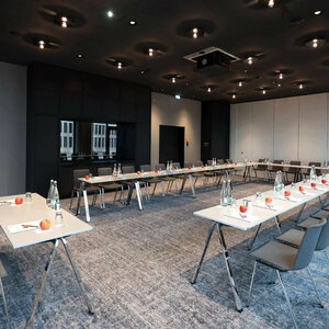 Moderner Konferenzraum im ATLANTIC Hotel Heidelberg mit U-förmiger Bestuhlung, Wasserflaschen und Äpfeln auf den Tischen.
