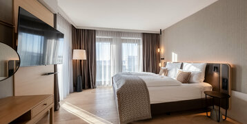 Blick auf das Bett und die sonnendurchfluteten Fenster