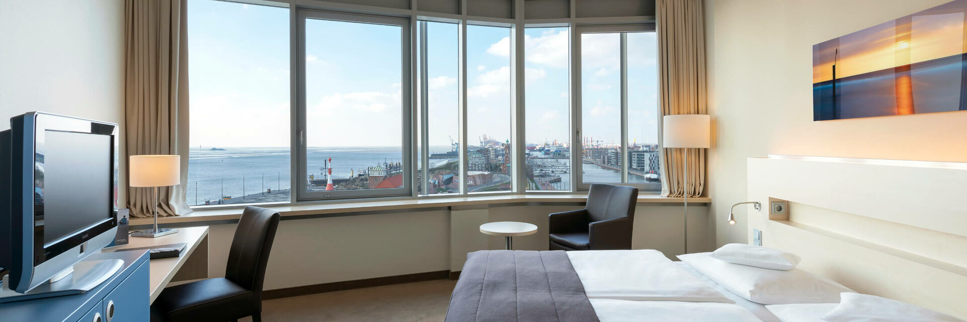 Helles Hotelzimmer mit Doppelbett, großem Fenster und Blick auf den Hafen von Bremerhaven.