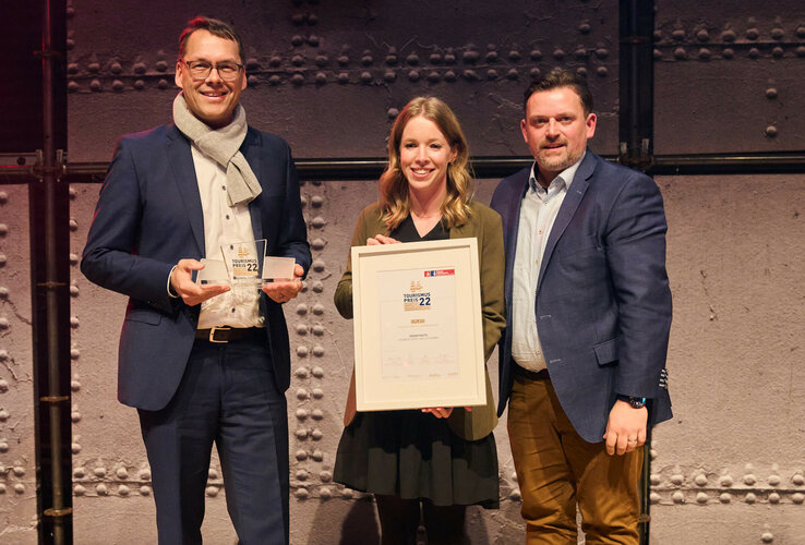Three people receive an award and a certificate at the ATLANTIC Hotel Sail City, Bremerhaven.
