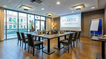 Moderner Konferenzraum im ATLANTIC Grand Hotel Bremen mit U-förmiger Bestuhlung, Präsentationsleinwand und Flipchart.