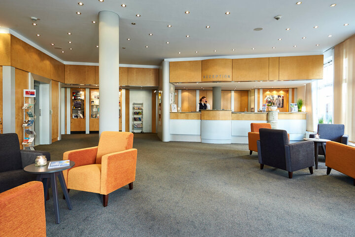 Empfangsbereich im ATLANTIC Hotel Vegesack in Bremen Helle Hotel-Lobby mit Rezeption, gemütlichen Sitzbereichen und moderner Einrichtung im ATLANTIC Hotel Vegesack, Bremen.