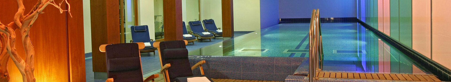 Wellness area with a pool in the ATLANTIC Grand Hotel Travemünde Modern indoor pool with sun loungers and atmospheric lighting at the ATLANTIC Grand Hotel Travemünde.