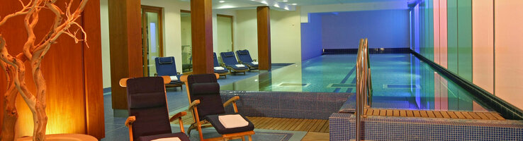 Modern indoor pool with sun loungers and atmospheric lighting at the ATLANTIC Grand Hotel Travemünde.