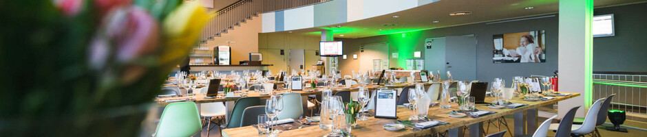 Modernes Restaurant im ATLANTIC Hotel Sail City, Bremerhaven, mit gedeckten Holztischen und stilvoller Beleuchtung.