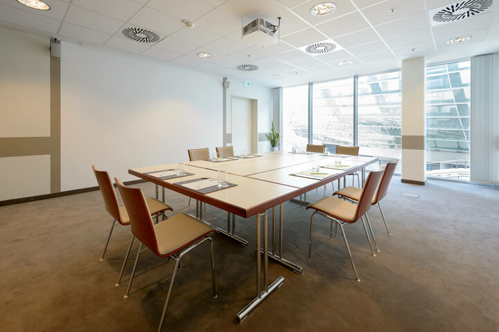 Modern conference room with large table, eight chairs and panoramic window in the ATLANTIC Hotel Sail City Bremerhaven.