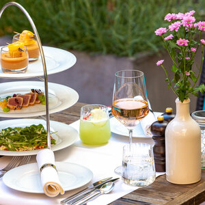 Elegant gedeckter Tisch im ATLANTIC Grand Hotel Bremen mit Etagere, Getränken und Blumenarrangement.
