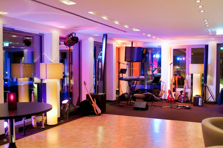 Feier auf DECK 8 – die Bar Bühne im ATLANTIC Hotel Kiel mit Instrumenten, Mikrofonen und bunter Beleuchtung, bereit für Live-Musik.