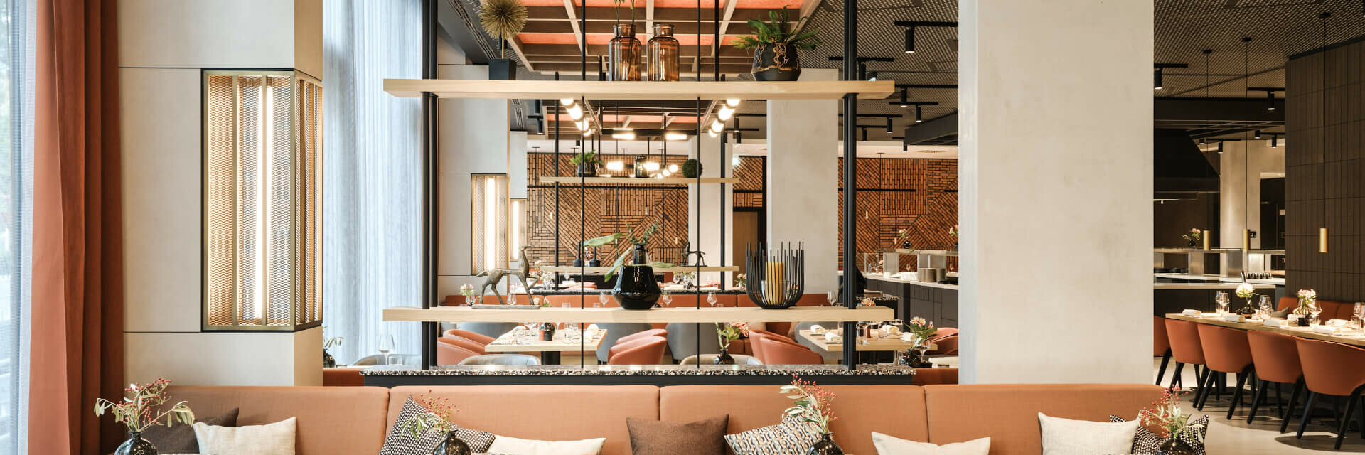 Modernes Restaurant im ATLANTIC Hotel Münster mit stilvollen Tischen, bequemen Sesseln und dekorativen Pflanzen.