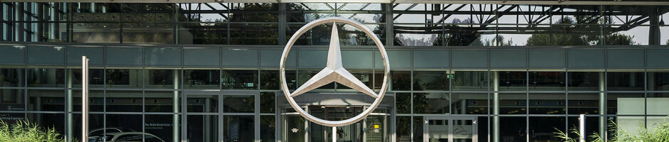 Modern glass façade with large, silver Mercedes star above the entrance.