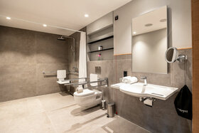 Barrierefreies Badezimmer im ATLANTIC Hotel Heidelberg mit Dusche, WC und Waschbecken, ausgestattet mit Haltegriffen.