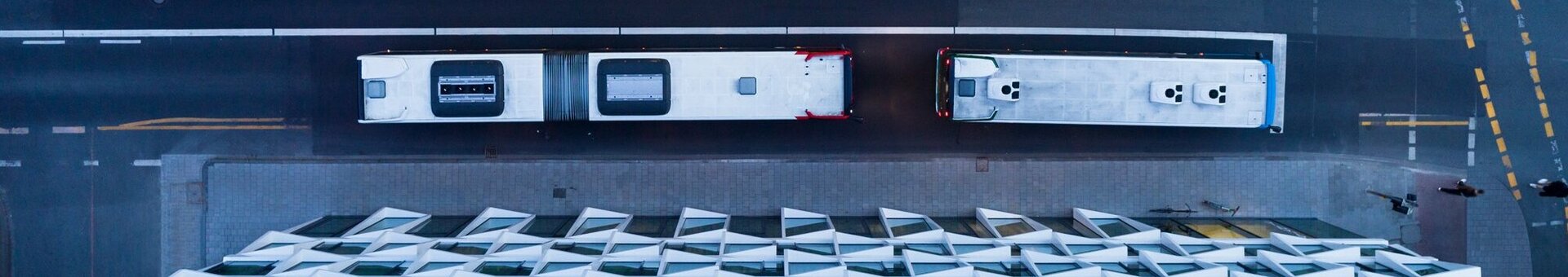 Aerial view of the ATLANTIC Hotel Münster with geometric facade, two buses on the street and marked bus lanes.