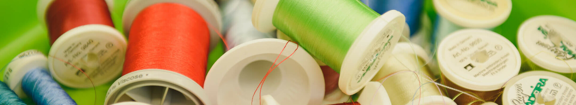 Upcycling Initiative | ATLANTIC Hotel Sail City Colorful spools of thread in a green box symbolize creativity and craftsmanship at the ATLANTIC Hotel Sail City.