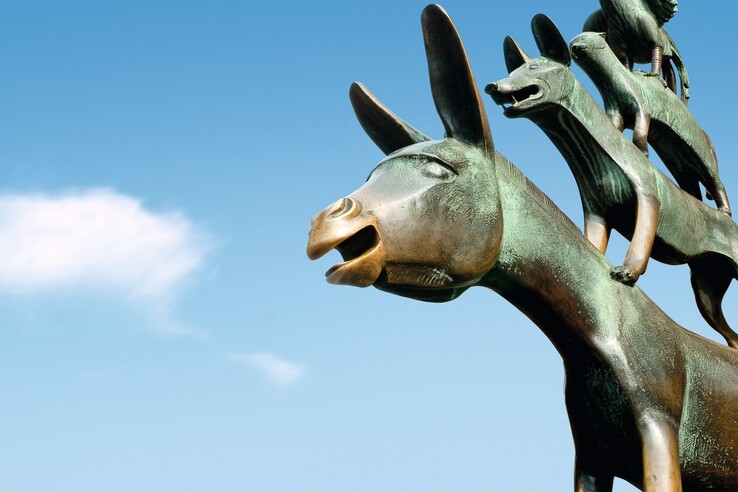 Bronzestatue der Bremer Stadtmusikanten, Tiere übereinander gestapelt, vor blauem Himmel.