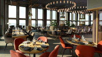 Modernes Hotelrestaurant mit eleganten Holztischen, roten und grauen Stühlen, großen Fenstern und stilvollen Hängelampen.