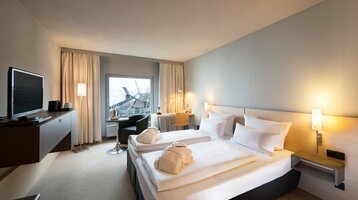 Modernes Hotelzimmer mit Doppelbett, Schreibtisch, Flachbild-TV und Fenster mit Blick auf das Universum Bremen.