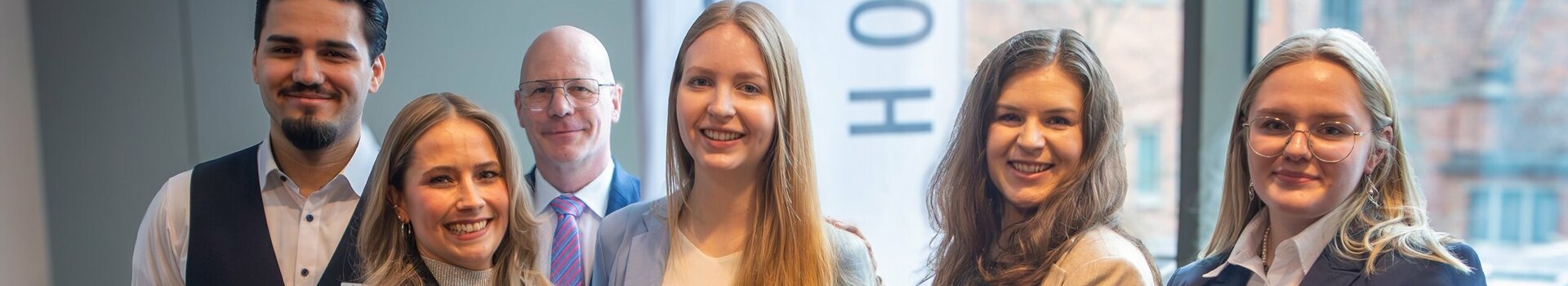 Eine Gruppe von sechs Hotelmitarbeitern hält stolz ein Zertifikat in einem modernen Raum.