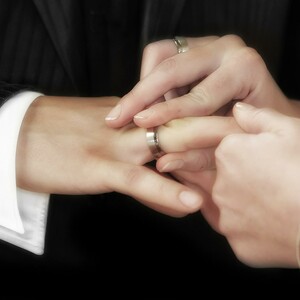Free wedding ceremony Close-up of hands putting a wedding ring on a finger, symbolizing marriage.