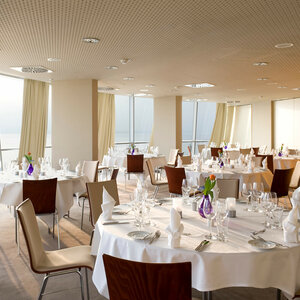 Celebrate in room Deck 1 south of the ATLANTIC Hotel Sail City Elegant restaurant with laid tables, white tablecloths, glasses and a view of the sea at the ATLANTIC Hotel Sail City.