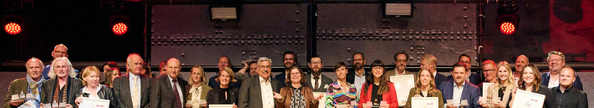 A group of people on a stage holding certificates, above them a banner with "Tourismus Preis 22 Bremen Bremerhaven".