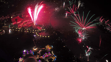 Feuerwerk über dem ATLANTIC Grand Hotel Travemünde bei Nacht, mit Menschenmengen und beleuchteten Zelten im Vordergrund.