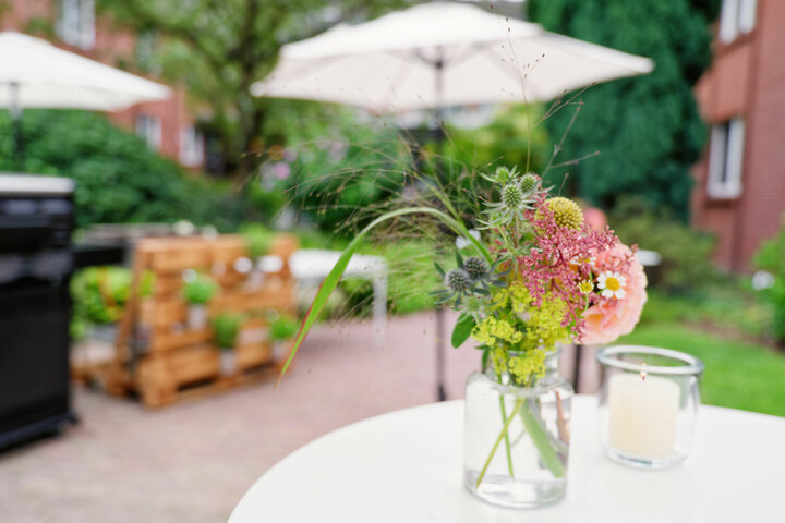 Vase with a colorful bouquet of flowers on a table in the green garden of the ATLANTIC Hotel Landgut Horn Bremen.