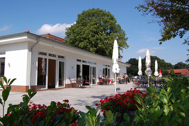 Clubbhaus Vegesack, terrace with parasols and flowering plants in sunny weather.