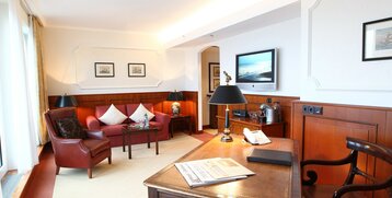 Living room with a sofa and desk in the Cutty Sark Suite in the ATLANTIC Hotel Wilhelmshaven
