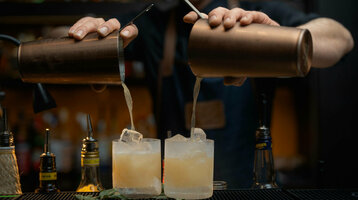 Bartender mixes cocktails at the bar of the ATLANTIC Grand Hotel Bremen, two glasses are filled at the same time.