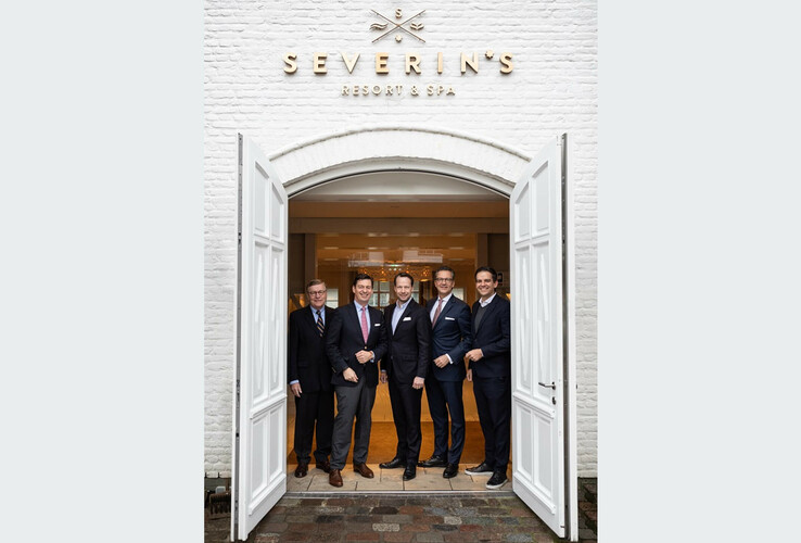 Fünf Männer in Anzügen stehen lächelnd im Eingang von Severin's Resort & Spa.