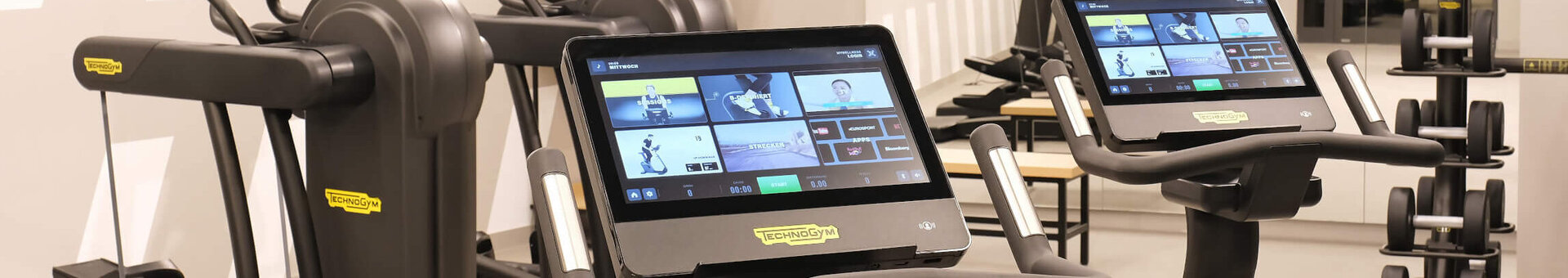 Modern fitness room at the ATLANTIC Hotel Münster with treadmills, screens and weights.