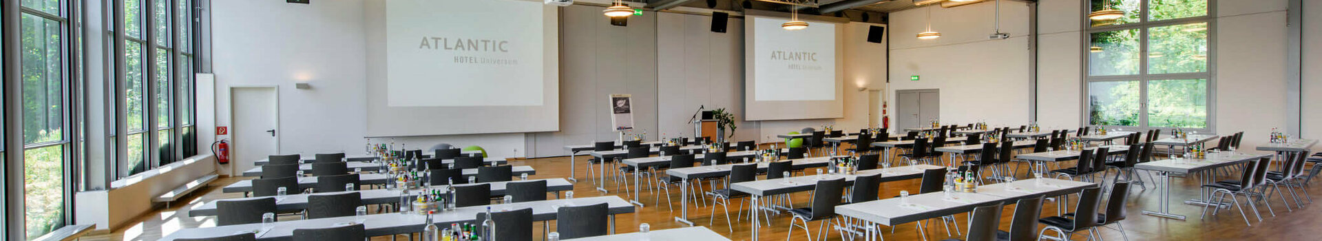 Modern conference room in the ATLANTIC Hotel Universum with tables, chairs and large windows.