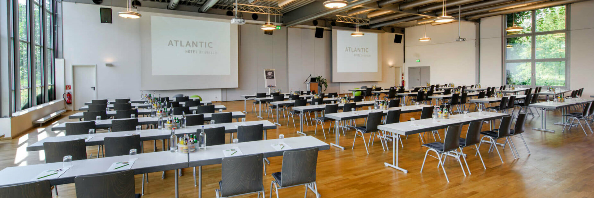 Modern conference room in the ATLANTIC Hotel Universum with tables, chairs and large windows.